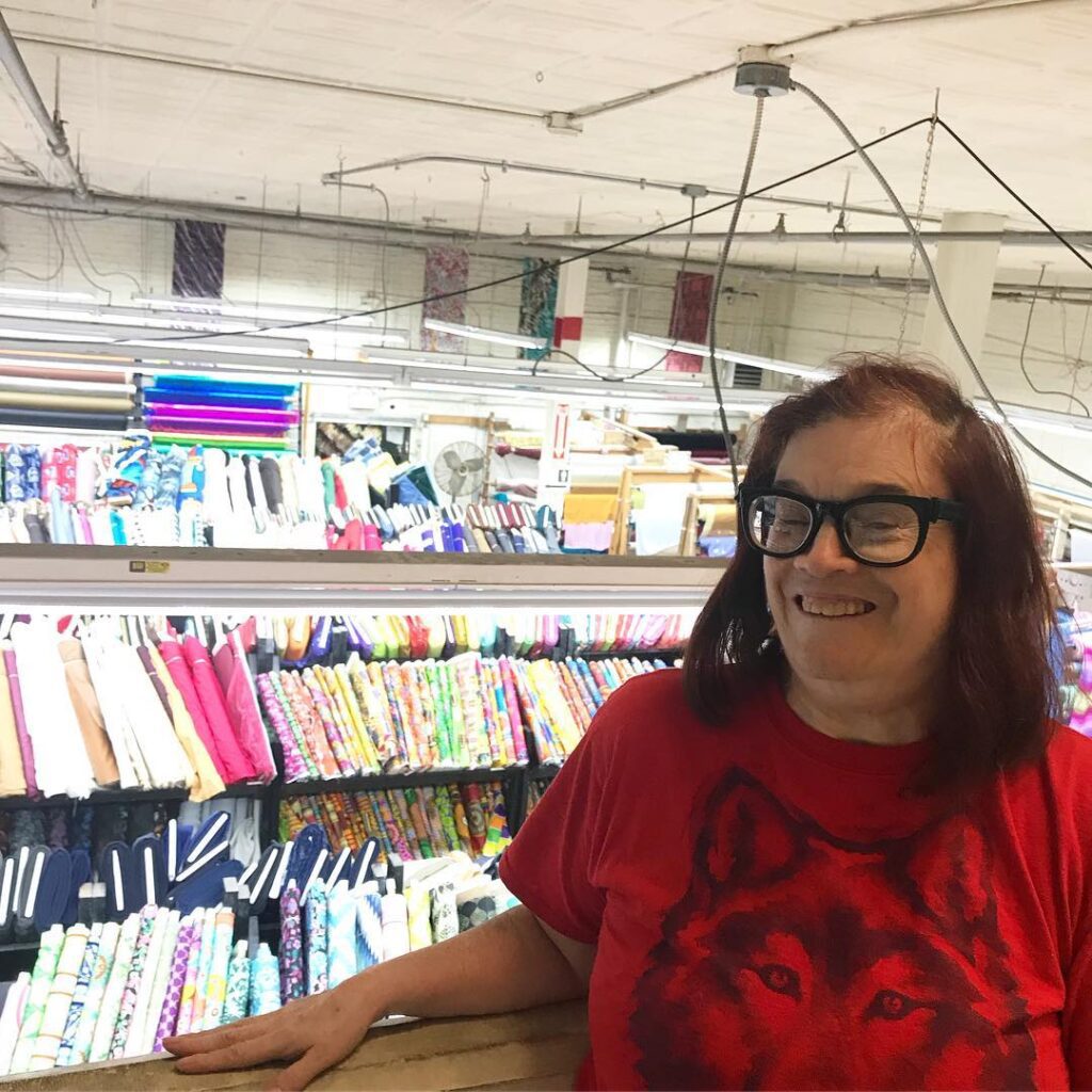 L'Arche member in a fabric shop ready to buy material for their artwork